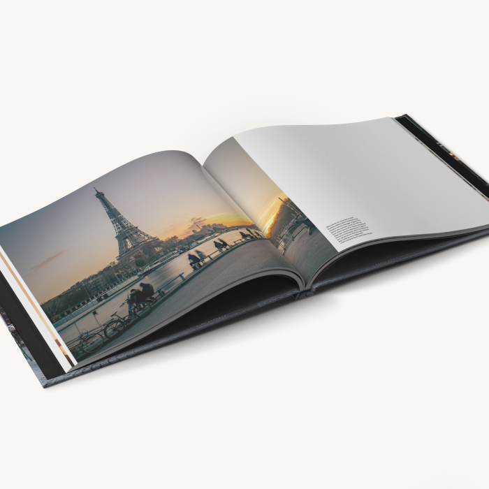 ImageWrap hardcover photo book opened to a wide panoramic image of the Eiffel Tower covering three-quarters of the spread with text on the right hand side.